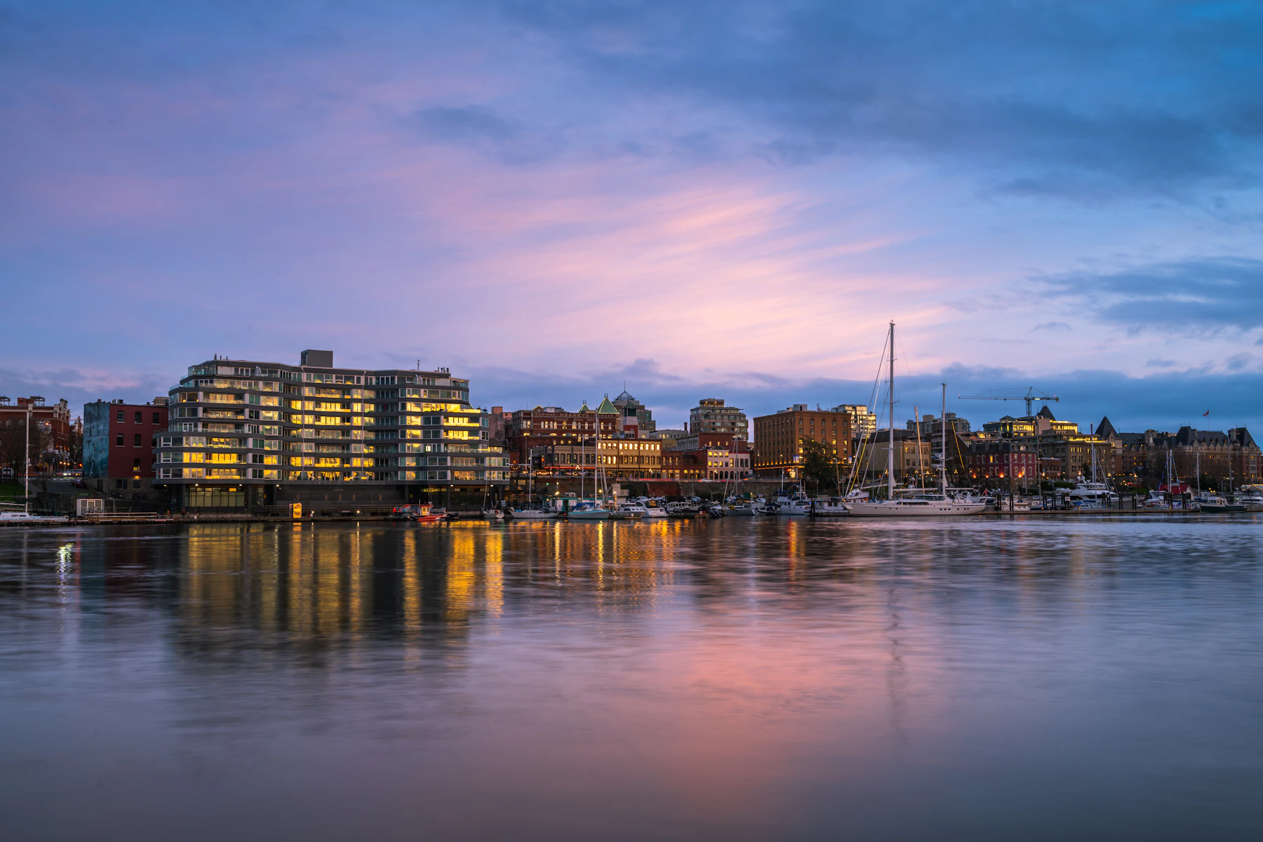 Victoria’s downtown waterfront and sailboats in the Inner Harbour at dusk.